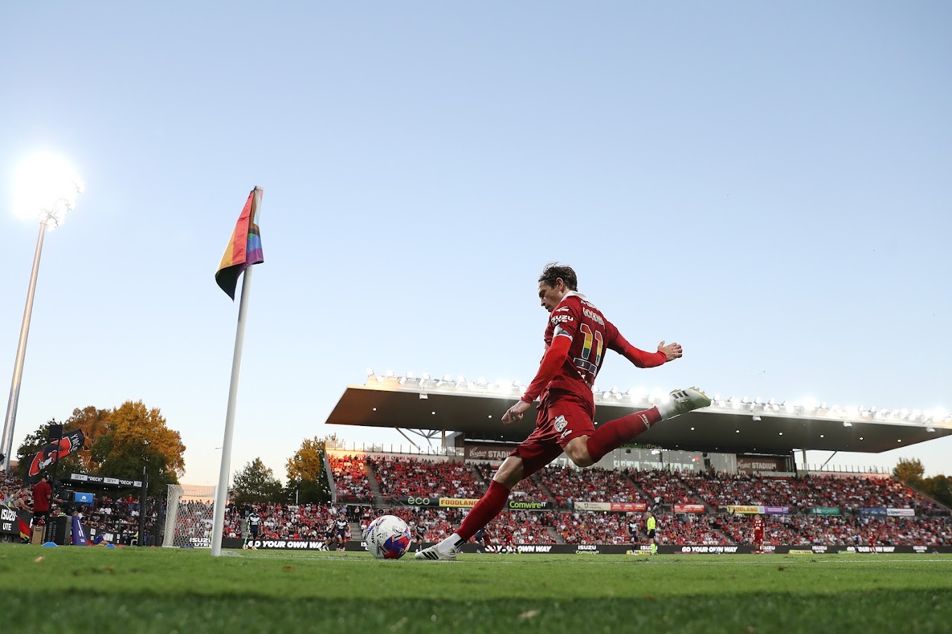 An Adelaide United player taking a corner kick beside the pride corner flag at Coopers Stadium